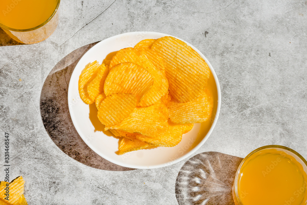 potato crisps served in a white bowl, beer snacks on a gray background potato crisps served in a white bowl, beer snacks on a gray background