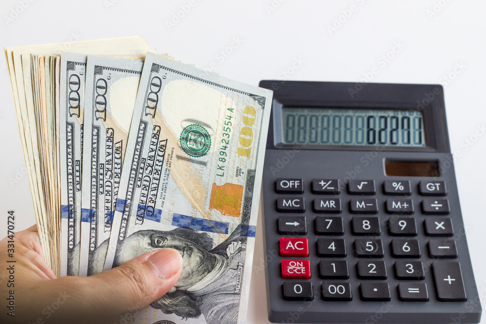 Holding American Banknotes on the calculator and numbers writting on it.White background. Holding American Banknotes on the calculator and numbers writting on it.White background.