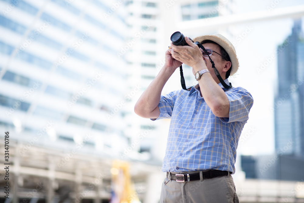 Fototapeta premium An asian elder man travel in the city with camera. He is healthy and happy. Health care , life style, pharmacy, medical, elder insurance after retire concept.