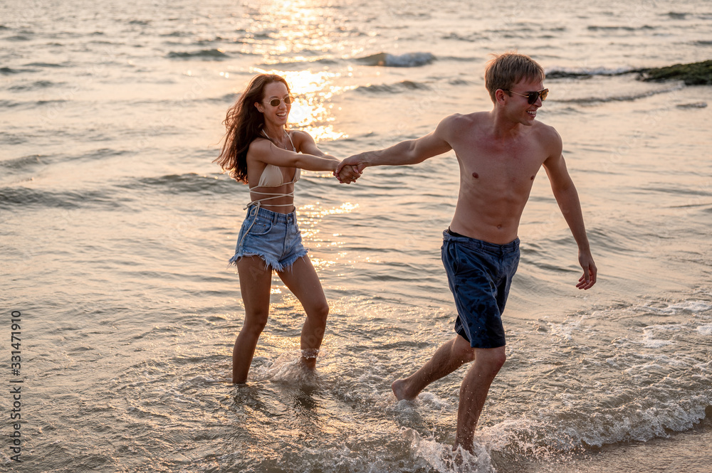 Couple caucasian and latin are walk together at the beach with sunset. Summer vacation relaxation, travel, nature, happy life unseen concept.