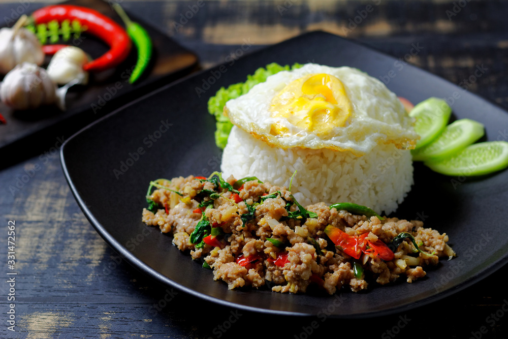 Stir fried Thai basil with minced pork and a fried egg on dark background Stir fried Thai basil with minced pork and a fried egg on dark background