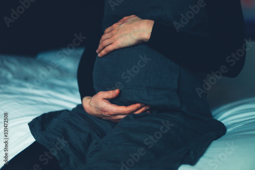 Pregnant woman with eczema on her hands sitting on bed