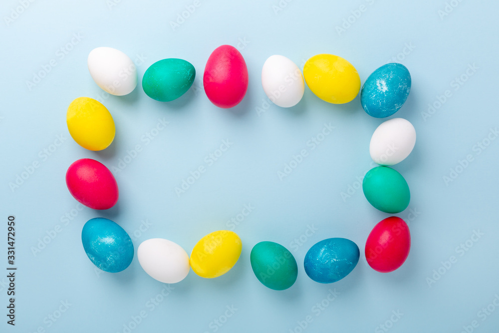 Frame of multicolored easter eggs on blue background. Easter composition. Copy space. Mockup