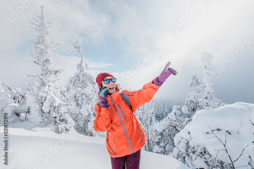 A happy girl uses a smartphone high in the mountains at winter time. Concept of wireless communication and connection