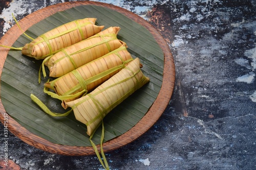 Lepet, Javanese cuisine, Indonesian dessert. Sticky rice dumpling with black beans cooked in coconut milk wrapped in young coconut leaf photo