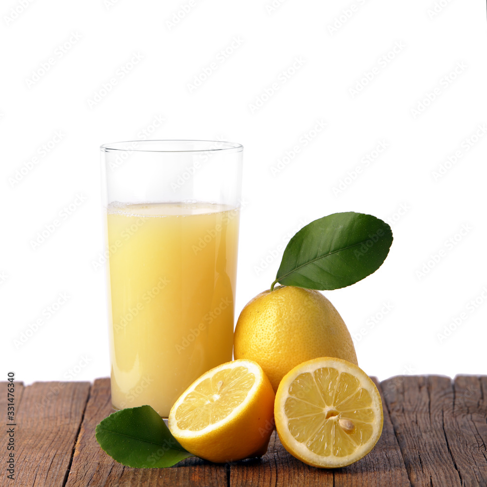 Bicchiere in vetro pieno di succo al limone su un piano in legno e limoni freschi Bicchiere in vetro pieno di succo al limone su un piano in legno e limoni freschi