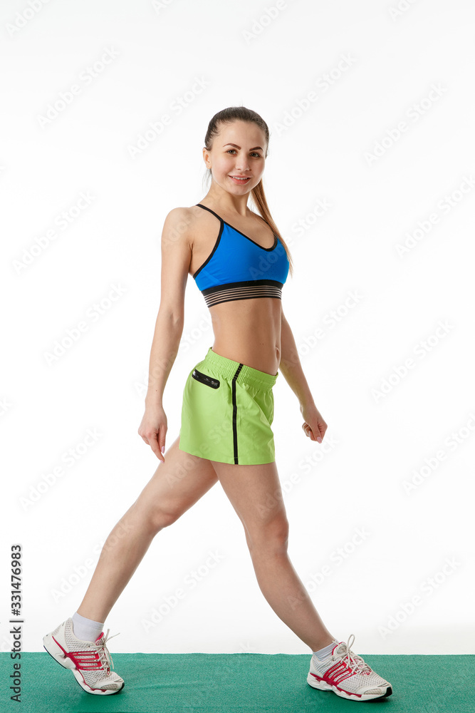 a girl in sports clothes on a Mat sports poses on a white background