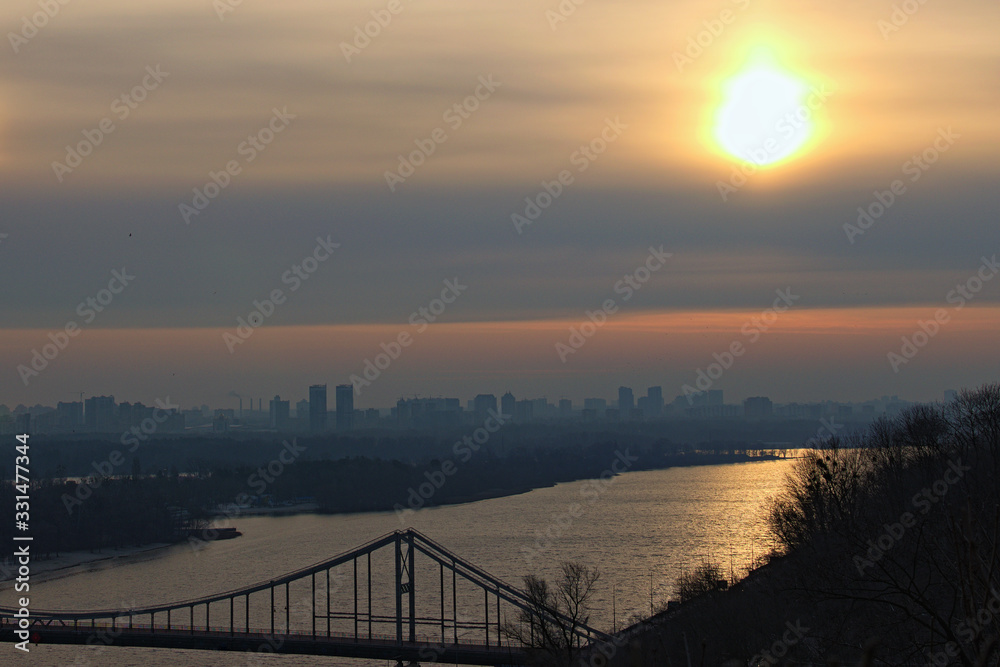 Astonishing landscape view of Dnipro River with the Pedestrian Bridge during spring colorful sunrise. Buildings with morning mist in the background. Saint Vladimir Hill. Kyiv, Ukraine