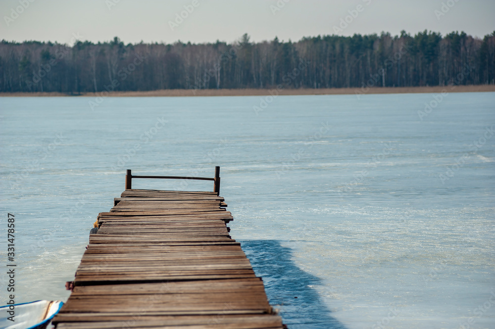 Obraz premium Closeup of the old pier on the frozen lake