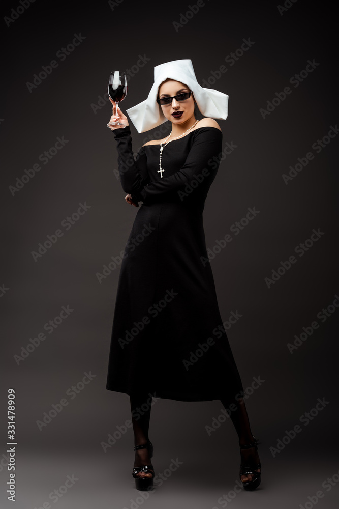 attractive sexy nun in sunglasses holding glass of red wine on grey attractive sexy nun in sunglasses holding glass of red wine on grey