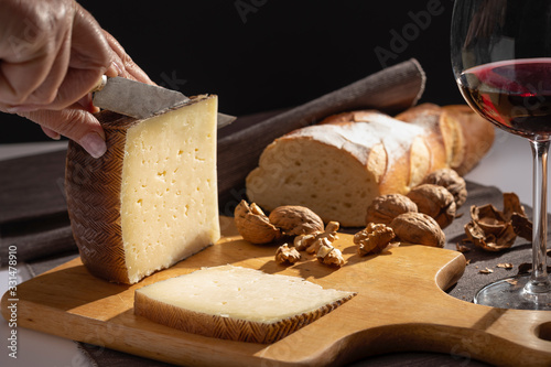 Manchego cheese and nuts on wooden table. photo