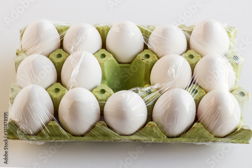Fresh organic white color eggs on the fifteen cardboard wrapped in stretch film and a place is empty.