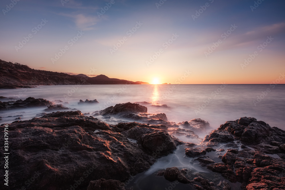 Fototapeta premium Waves washing onto rocky Corsica coastline at sunset