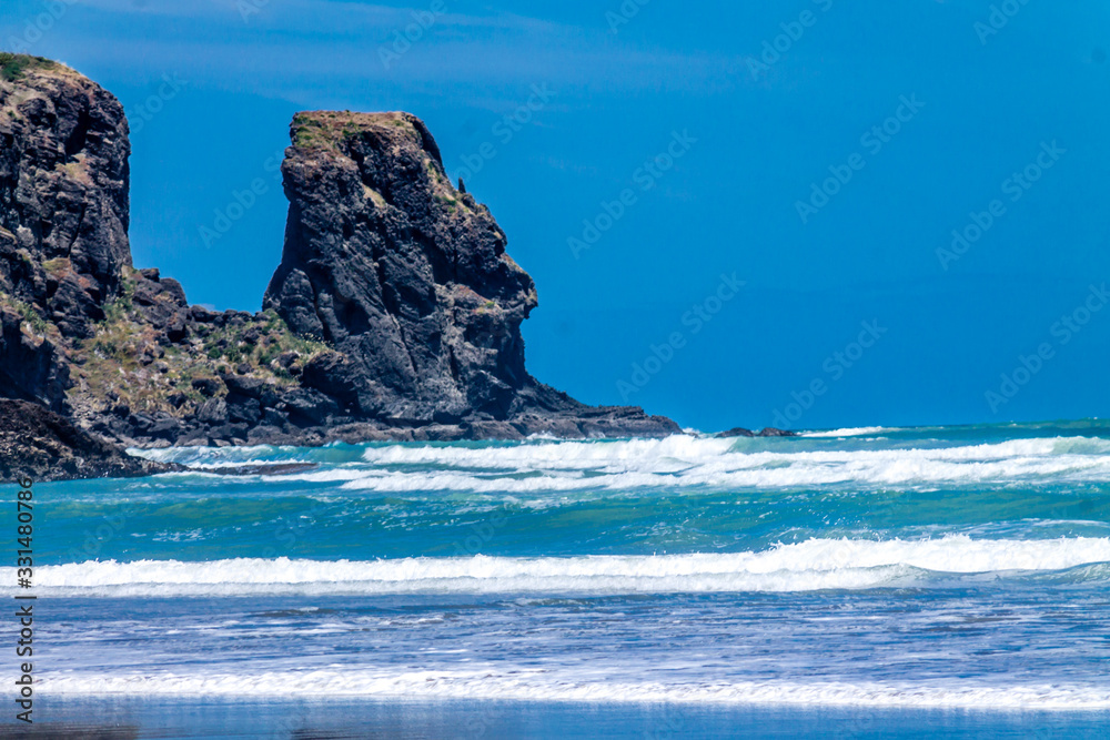 Sandy beaches, cliffs and rolling water on Bethels Beach. Auckland, New Zealand