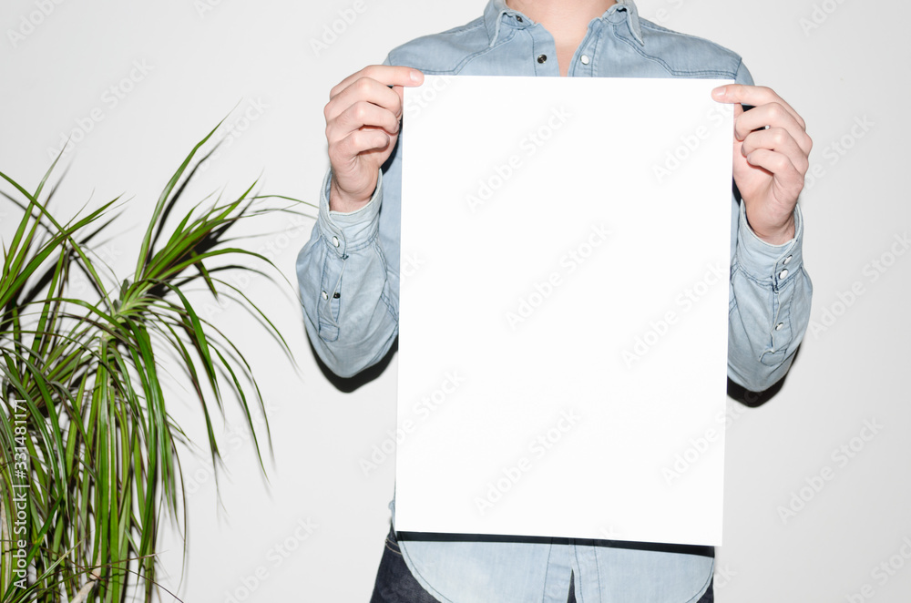 A3 Poster Mock-Up - Man in a denim shirt holding a poster on a white  background. Hipster Aesthetic Stock Photo