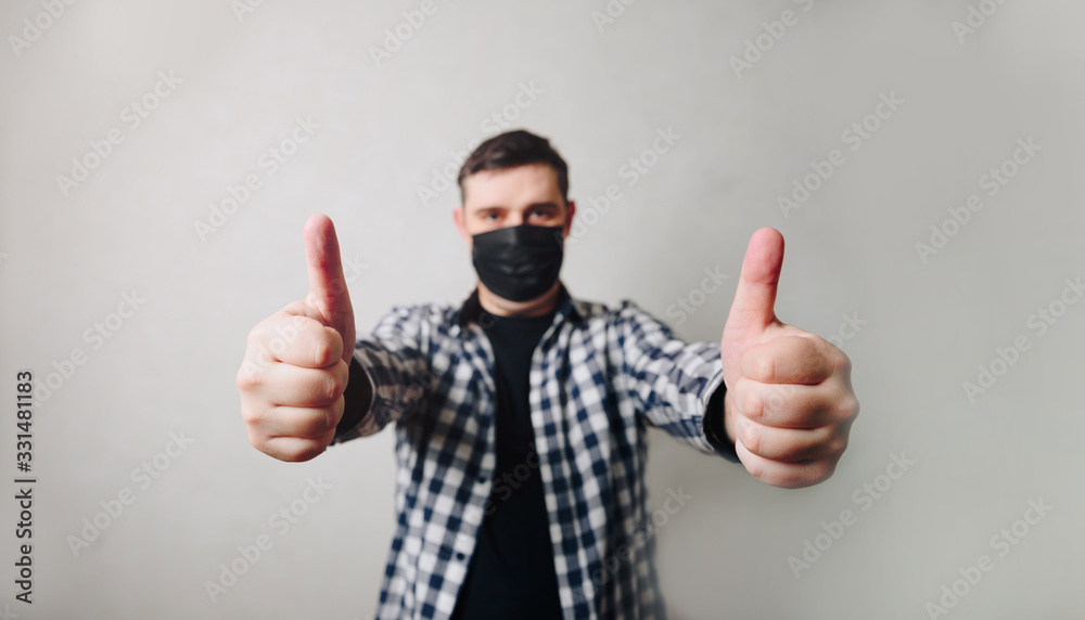 man in a shirt in a black medical mask on a gray background man in a shirt in a black medical mask on a gray background