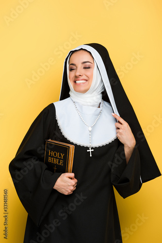 Tableau sur toile beautiful smiling nun holding holy bible on grey