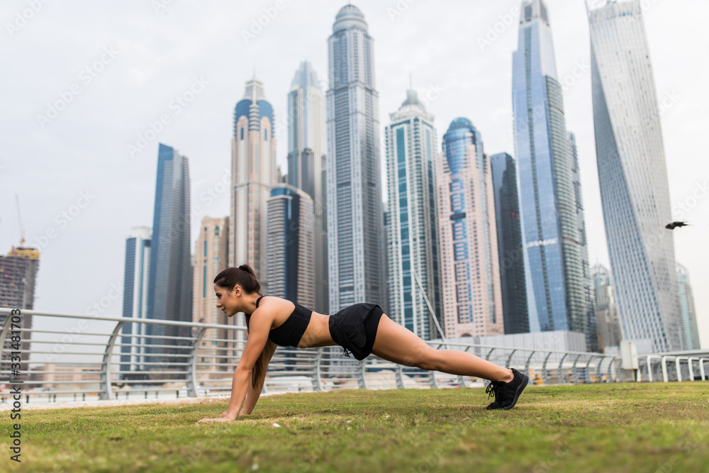Young fitness woman make plank exercises in front of skyscrapers