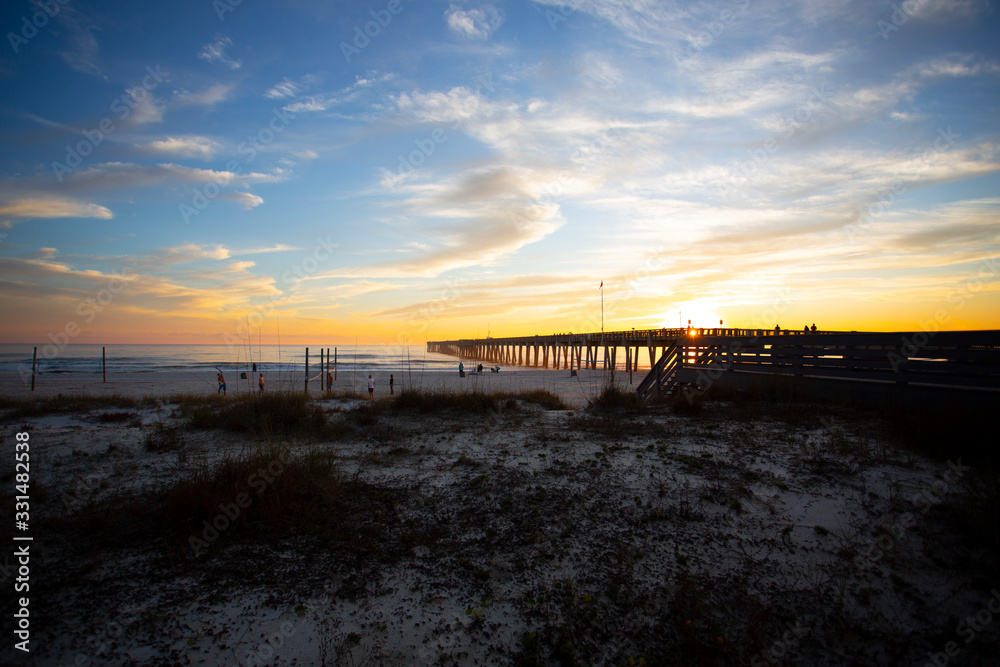 panama city beach florida ocean at shoreline with beautiul sunset clouds and pier into the water