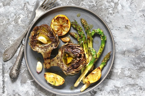 artichoke and asparagus grill. Tasty vegetables are first cooked for a couple, then fried on a grill, poured with olive oil and spices. spring vegetables. background concrete. top view.  copy space. 