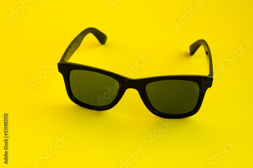 Stylish Black Color Sunglasses on the yellow surface with copy space,close up