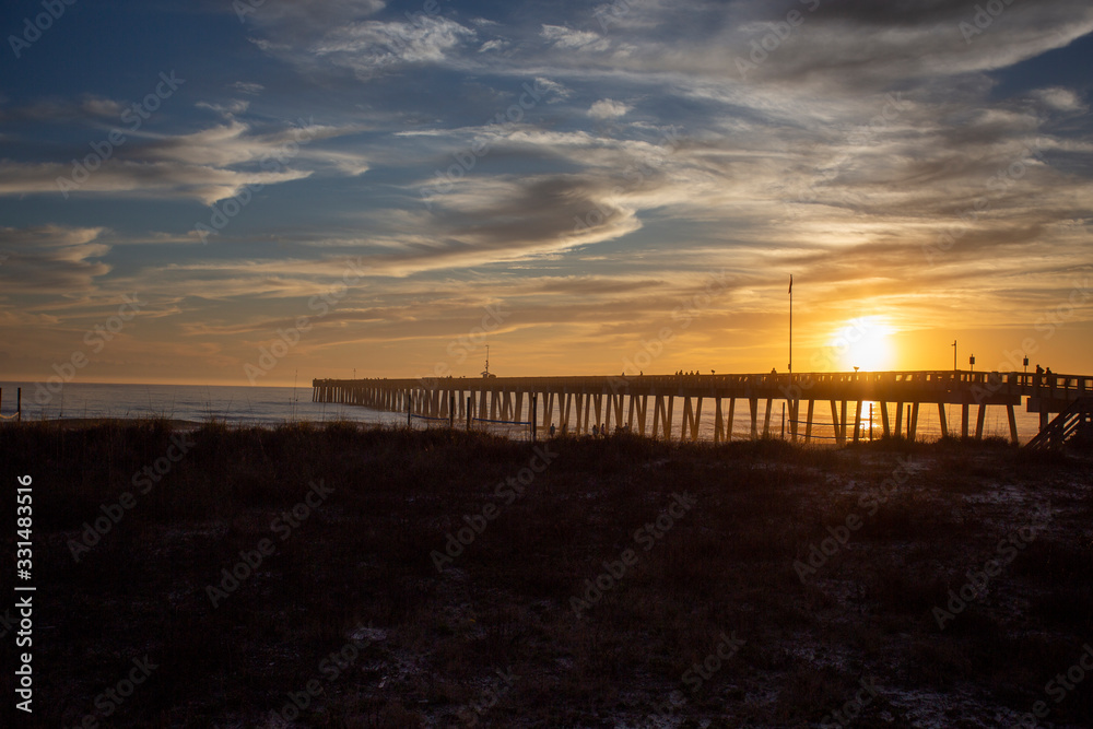 panama city beach florida ocean at shoreline with beautiul sunset clouds and pier into the water