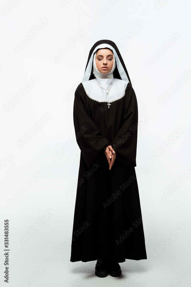 beautiful nun praying with closed eyes, isolated on white