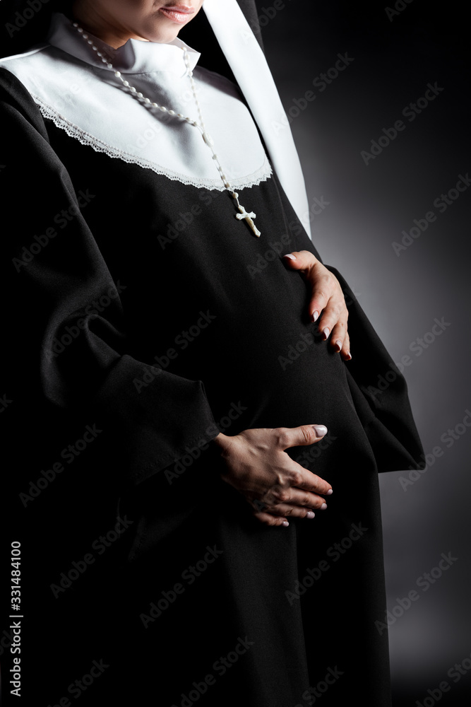 cropped view of pregnant nun touching tummy on grey cropped view of pregnant nun touching tummy on grey