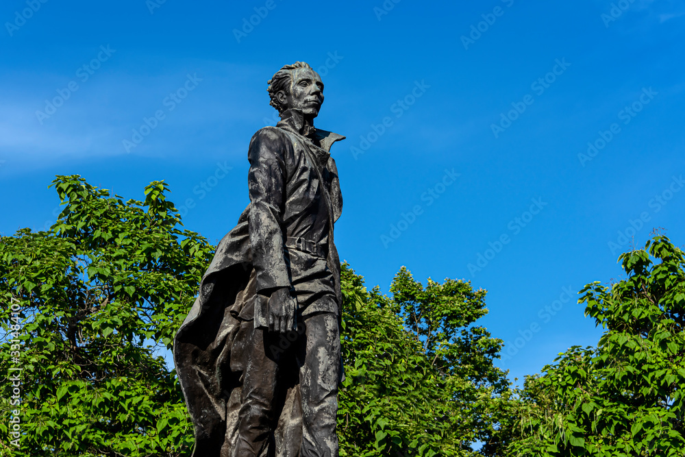 Russia, Black Sea, Sochi: Nikolai Ostrovsky statue monument in a public park in the city center of the Russian town with square, green trees, garden and blue blue sky - literature author culture