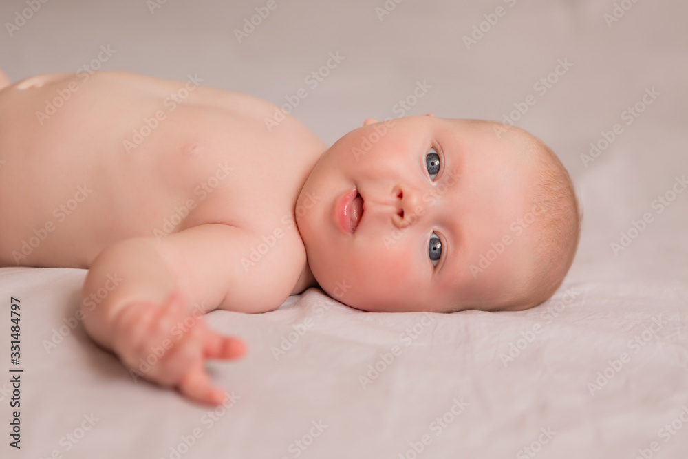Happy 3 months old baby smiling, lying on white bed Happy 3 months old baby smiling, lying on white bed