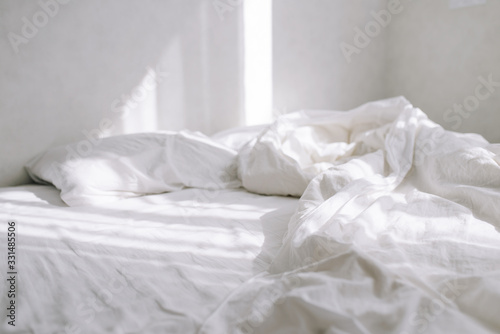 On a bed in a light bedroom the rays of the sun fall