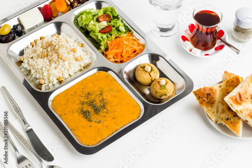 Ramadan iftar meal with soup rice with chicken chickpea vegetable salad dessert and dry fruits in the stainless steel portion food tray.Top view fulled frame.