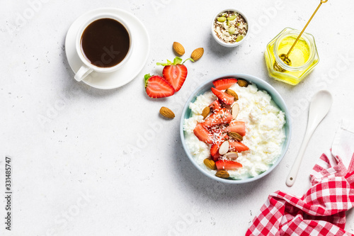 Fototapeta Naklejka Na Ścianę i Meble -  Healthy breakfast served, cottage cheese with strawberry and almonds, honey, cup og black coffee. Top view, copy space.