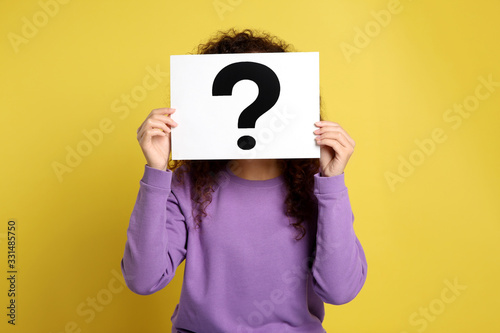 Woman with question mark sign on yellow background