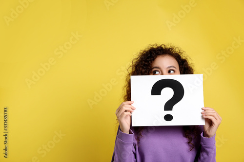 African-American woman with question mark sign on yellow background. Space for text
