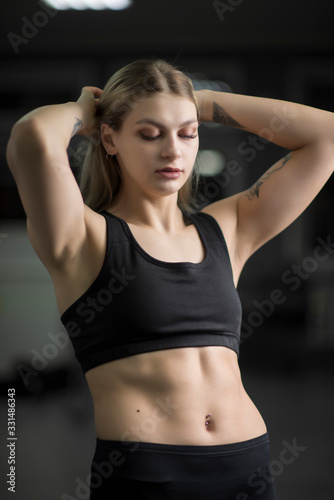 Fototapeta Naklejka Na Ścianę i Meble -  Closeup portrait of a sportswoman with blond hair with arms raised.
