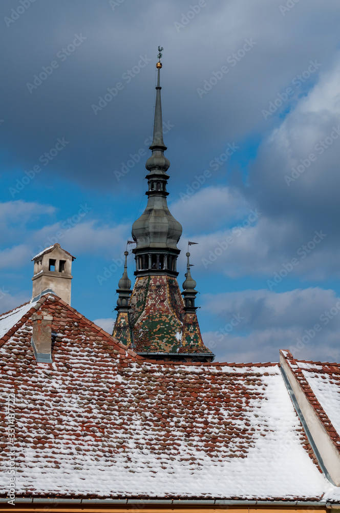 Obraz premium A rooftop and a church steeple. Rooftop covered with snow. Winter scene.