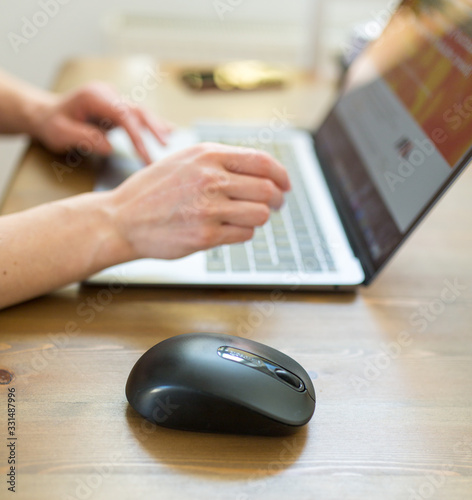 maus und Laptop mit Frauenhänden auf  Wohnzimmertisch