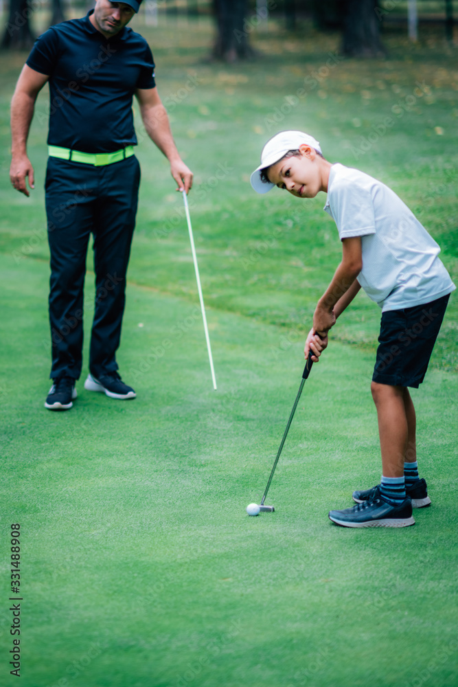 Fototapeta premium Golf Putting Training. Golf Instructor with Young Boy Practicing on the Putting Green