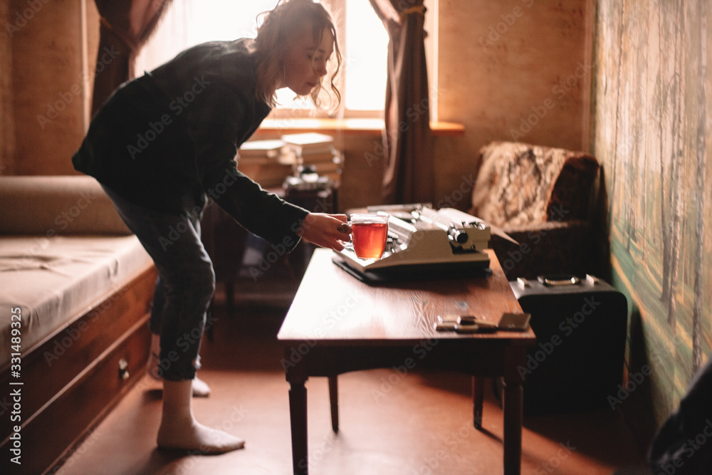 Young woman holding cup of tea standing in living room at home Young woman holding cup of tea standing in living room at home