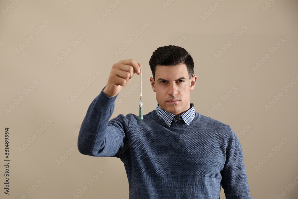 Psychotherapist with pendulum on beige background. Hypnotherapy session Psychotherapist with pendulum on beige background. Hypnotherapy session