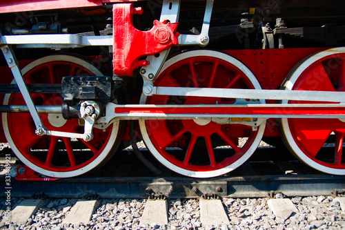 Red driving wheels of a vintage steam engine locomotive. Driving rods, drives, cranks and other parts. The history of railway transport.