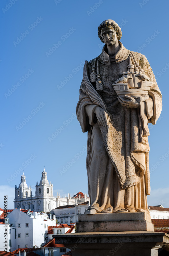 Obraz premium Saint Vincent, statue in Miraduro de Santa Luzia, famous viewpoint of Lisbon, Portugal, with che church of Sao Vincente de Fora on background