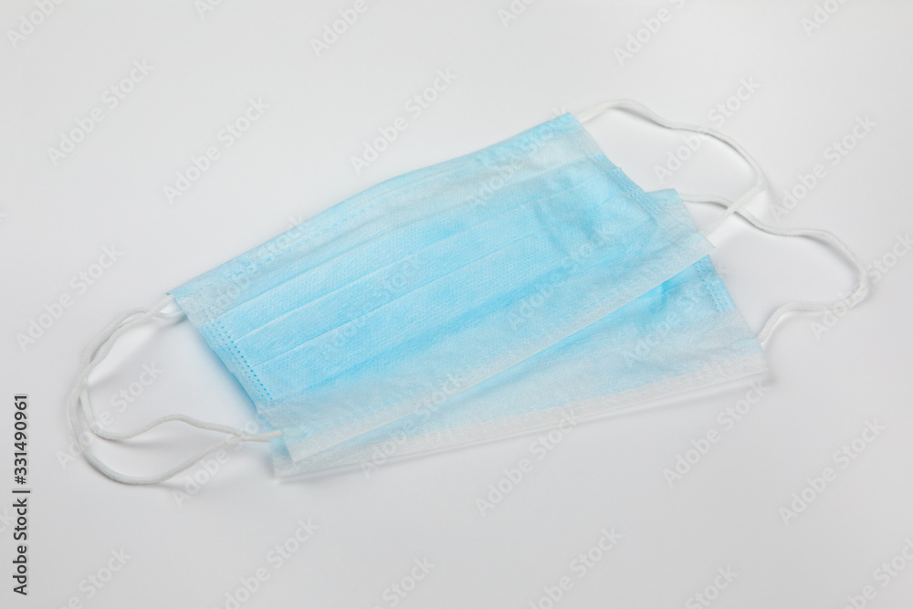 Coronavirus prevention. Two typical 3-ply blue surgical medical masks lying diagonally on top of each other on white background. Hygiene corona virus protection concept. Coronavirus prevention. Two typical 3-ply blue surgical medical masks lying diagonally on top of each other on white background. Hygiene corona virus protection concept.