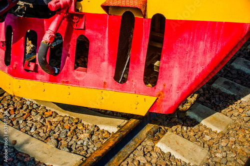 Cowcatcher of a vintage diesel engine locomotive painted red and yellow. Rusty rails. The history of railway transport.