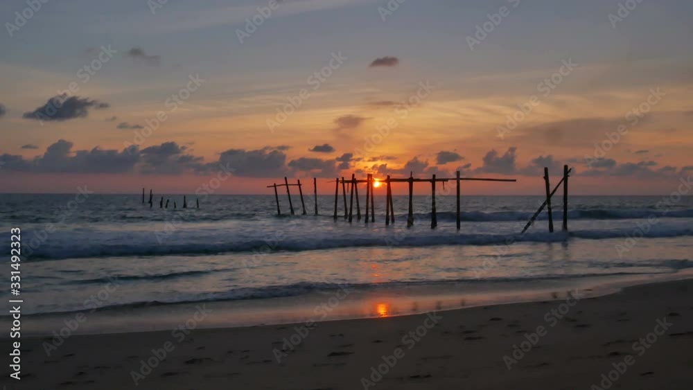 moving wave to sand sea beach , ruin rusty steel pole of old harbor. hot golden reflection sun light in water and beautiful cloudy blue sky horizon background at evening day time, Phanganga Thailand moving wave to sand sea beach , ruin rusty steel pole of old harbor. hot golden reflection sun light in water and beautiful cloudy blue sky horizon background at evening day time, Phanganga Thailand
