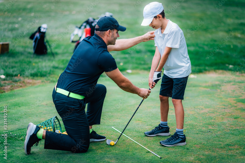 Obraz premium Golf Lessons. Golf instructor giving game lesson to a young boy.