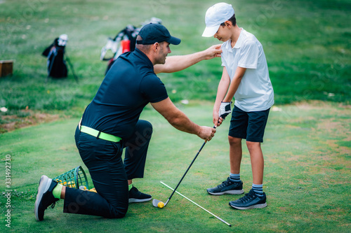 Fototapeta Golf Lessons. Golf instructor giving game lesson to a young boy.