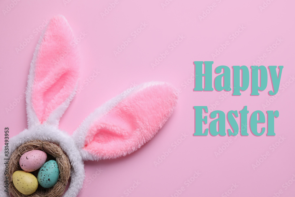 Easter bunny ears headband and dyed eggs in nest on pink background, flat lay