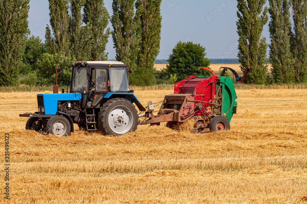 tractor makes big straw roll on yellow field at summer day tractor makes big straw roll on yellow field at summer day